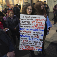 A woman holds a sign with writing in Spanish