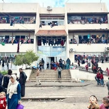 Clothes can be seen hanging from the balconies of and many people can be seen near the entrance of the Palestine Technical College in central Gaza  