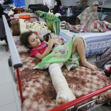 A girls plays on a phone in hospital bed, her leg in plaster