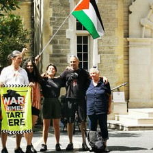 Some members of the campaign group Palestine Action hold a banner reading war crimes start hear and a Palestinian flag outside a London court 
