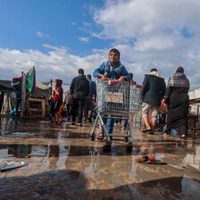 A boy pushes a shopping cart in a puddle of rainwater