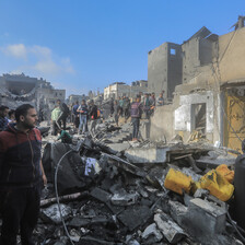 People stand in what remains of buildings following an Israeli airstrike 