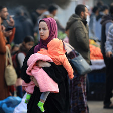 A woman carries a child after fleeing her home in Gaza 