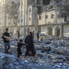 A number of people walk in the rubble of Gaza's Hamad City after it was attacked by Israel 