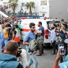 A medic carries an injured child beside an ambulance in the grounds of al-Shifa hospital, Gaza City 