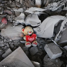 Amid the rubble osf a destroyed building is a stuffed teddy bear with a heart
