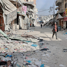 Some people walk amid destroyed and badly damaged buildings in the southern Gaza city of Khan Younis 