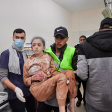 A medic wearing a yellow vest carries a girl who has been injured during Israel's war against Gaza