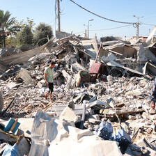 Men pick their way through the rubble of a destroyed building