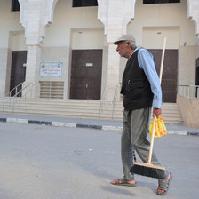 A man carries a broom down a street