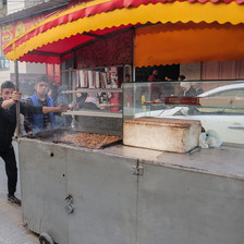 A boy pushes a food stall as another boy walks beside him 