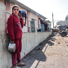 A child holding a pot looks into the camera