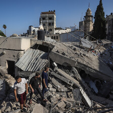 Three men stand in the remains of a building beside a Gaza church 