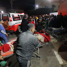 Health workers carry an injured patient on a stretcher beside an ambulance 