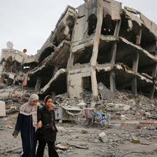 Two women walk beside a building that has been badly damaged in an Israeli airstrike 