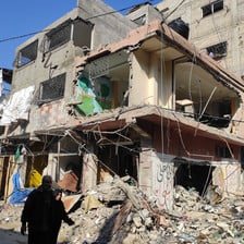 A man and a woman walk beside what remains of a building in Gaza 