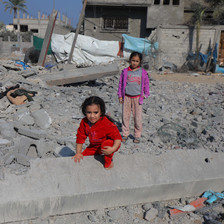 One girl kneels and one girl stands in Gaza's rubble 