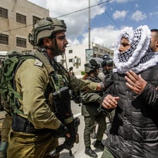 An Israeli soldier grabs the arm of a Palestinian demonstrator