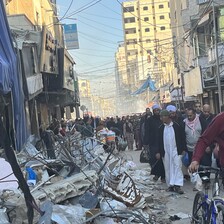 People crowd through a cityscape in ruins