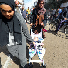 Two women push a stroller through crowded streets.