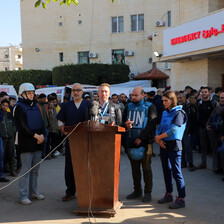 A man from the World Health Organization stands at a podium behind the Emergency sign of a Gaza hospital