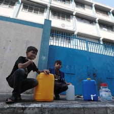 Boys kneel next to their water containers