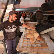 A baker removes loaves of flat bread from the oven