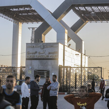 A number of men gather around a structure with the words Rafah Crossing Point written on it