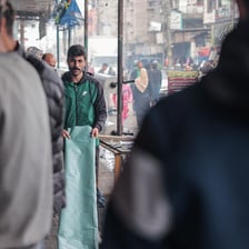 A man walks with a plastic sheet in a crowded street