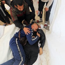 A man cries next to the body of his son