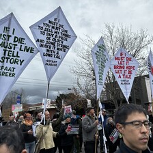 A number of kites bearing quotations from the poem If I Must Die are held up by people attending a protest 