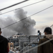Two people look at smoke rising after an Israeli airstrike in southern Gaza 