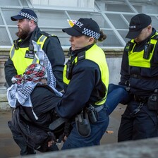 Three British police officers carry a demonstrator away