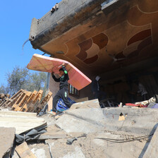 A boy carries an item on his head in the ruins of a building that has been bombed in Gaza