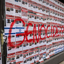 Posters bearing images of Israeli captives in Gaza with the word 'genocide' scribbled across