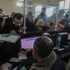 People crowd a window at a passport terminal