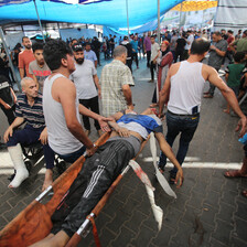 A number of men carry an injured man on a stretcher. 