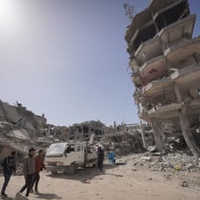 A few people next to destroyed and badly damaged buildings in the southern Gaza city of Khan Younis 