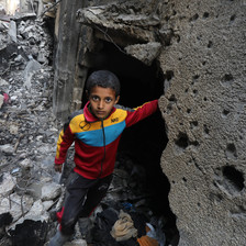 A boy wearing a track suit amid the ruins of a Gaza home destroyed by Israel 
