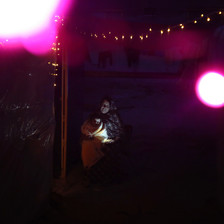 Two large pink lights glow in the dark, with a woman and child in the backgroud