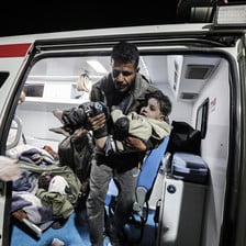 A medic carries an injured child out of an ambulance 