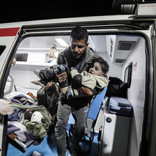 A medic carries an injured child out of an ambulance 