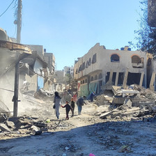 A few people walk amid what remains of buildings in Gaza City 