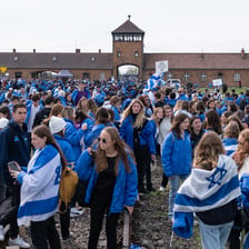 School children stand draped in Israeli flags outside Auschwitz