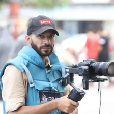 The photographer Mohammad Yaghi carrying a camera and wearing a vest marked Press 