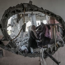 A woman can be seen through a hole in a badly damaged building 