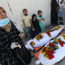 A woman and three children beside shrouded bodies in southern Gaza 