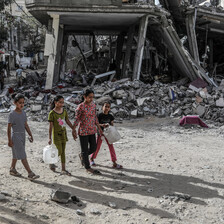 Children carry containers as they walk in front of a building attacked by Israel in southern Gaza 