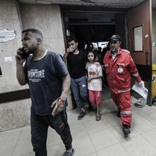 A medic walks beside a girl and a man in a Gaza hospital 