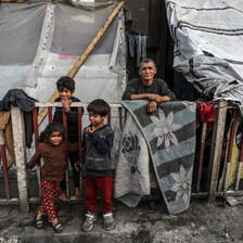 Three children and one adult stand beside a makeshift tent in southern Gaza 